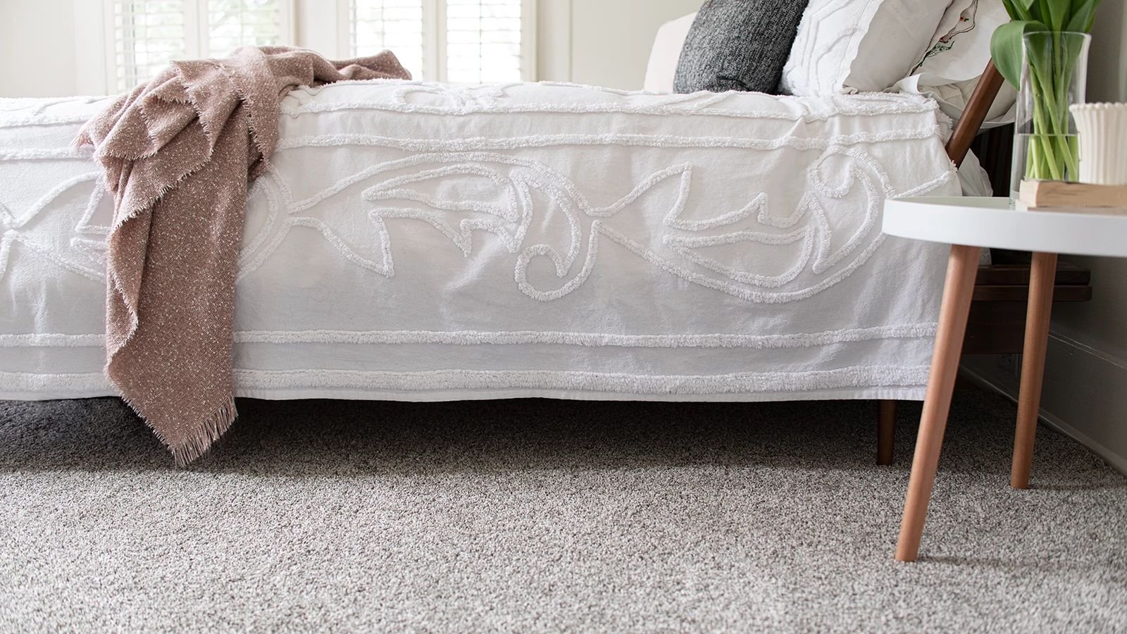 bed and nightstand in bedroom with grey carpet