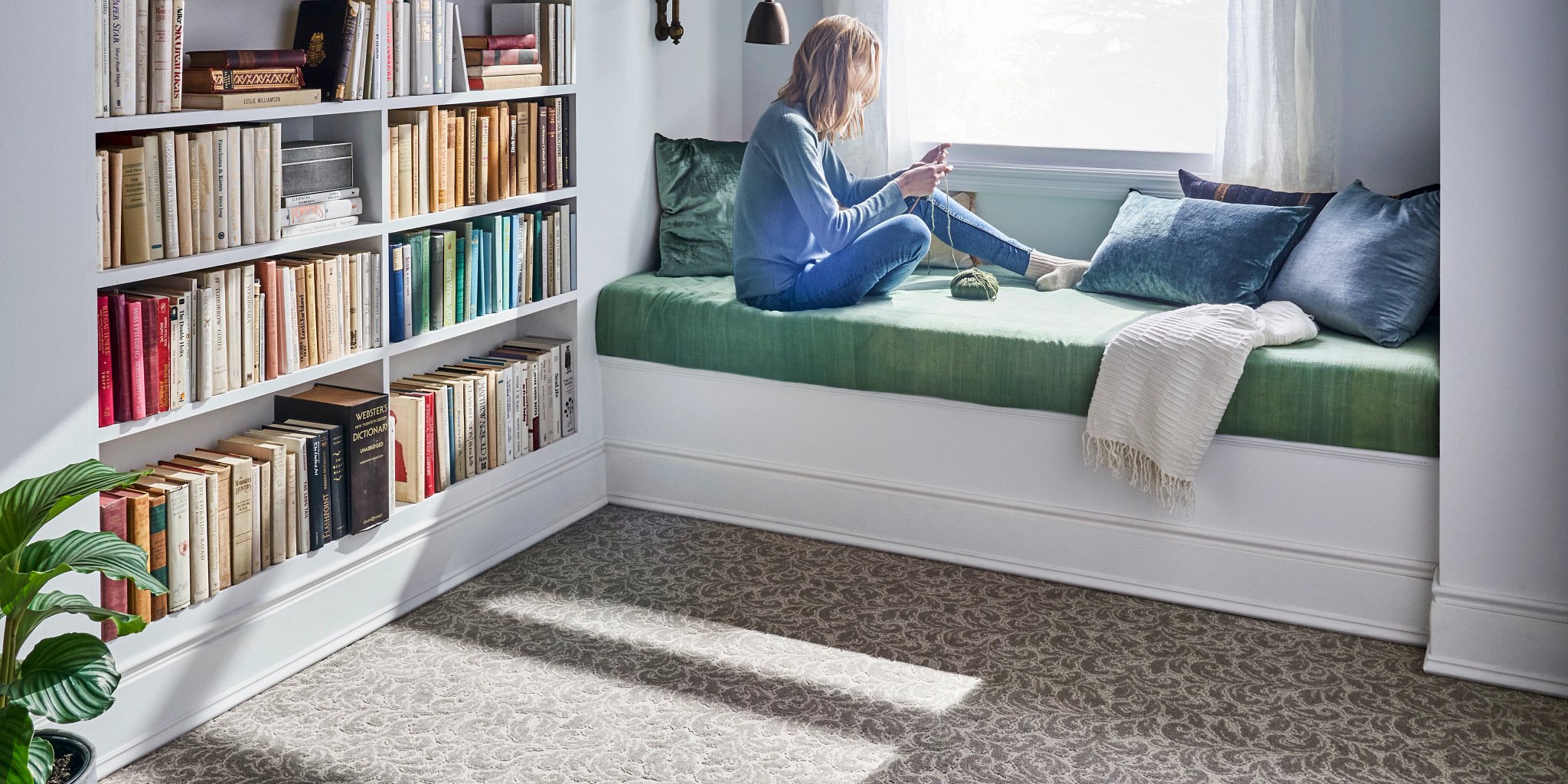 Woman sitting on bed near window reading a book